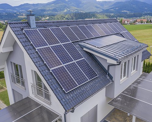 A high angle shot of a private house situated in a valley with solar panels on the roof